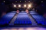 Aula de teatro con gradas azules y luces brillantes en el techo