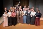 Grupo de actores vestidos con atuendos históricos posando en el escenario del teatro
