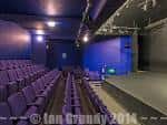 Vista lateral del teatro con asientos púrpuras y fondo azul en el escenario