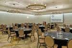 Sala de conferencias preparada para eventos con mesas redondas y proyector