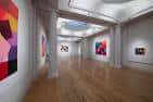Galería con columnas clásicas y obras de arte coloridas en las paredes