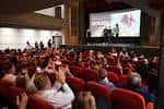 Interior del cine durante un evento con público sentado y pantalla iluminada