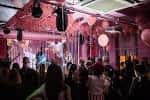 Interior del local durante un evento con iluminación rosa y público