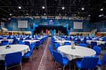 Sala de eventos principal con mesas redondas y sillas azules dispuestas para una conferencia o banquete
