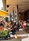 Terraza al aire libre con mesas y sombrillas amarillas en South Broadway