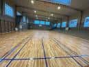 Vista interior del gimnasio con suelo de madera y canastas