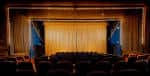 Interior del auditorio con cortinas doradas, butacas oscuras y escenario listo para eventos