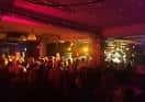 Interior del local durante un evento con público y escenario iluminado