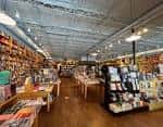 Interior amplio de la librería con estanterías llenas de libros y mesas de exhibición