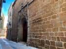 Fachada histórica de piedra con arco de entrada en la calle
