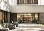 Entrada principal del edificio con fachada de concreto y cristal, zona de espera al aire libre
