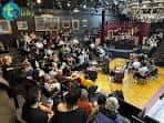 Evento en curso en el espacio interior de Theatre Three con público sentado alrededor de una zona central