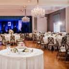 Sala de eventos del Junior League of Houston decorada para una recepción con mesas redondas y arañas