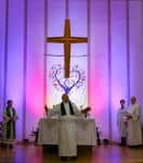 Interior del altar de la iglesia con cruz y decoración floral iluminada