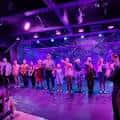 Grupo de personas en el escenario bajo luces púrpuras durante un evento