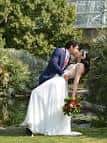 Pareja en boda celebrando un beso frente a invernadero tropical