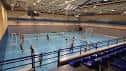 Pabellón deportivo interior con cancha de baloncesto y gradas azules