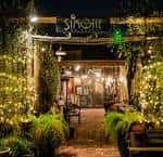 Entrada exterior de Simone on Sunset Houston con iluminación cálida y decoración vegetal