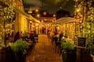 Patio interior del restaurante con mesas, luces colgantes y ambiente acogedor al atardecer