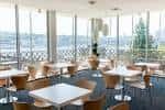 Sala de eventos con mesas y sillas junto a grandes ventanales con vista al agua
