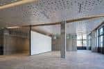 Espacio interior amplio y moderno con techo perforado y paredes de cristal