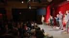 Escenario del teatro con cortinas rojas y público sentado durante una función