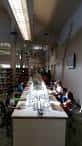 Interior de la biblioteca con mesas largas y personas estudiando