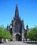 Vista frontal de la Catedral de Glasgow con su característica torre gótica bajo un cielo azul despejado