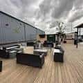 Área social exterior con mobiliario moderno en terraza de madera