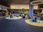 Área de descanso o lobby del cine con mesas, sillas y decoración moderna