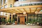 Entrada principal del hotel con toldo de madera y plantas decorativas