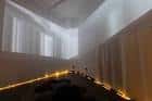 Vista interior del espacio expositivo con iluminación ambiental y paredes blancas