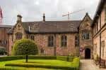 Vista exterior del edificio principal de Chetham's School of Music con fachada histórica y jardín bien cuidado