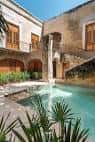 Piscina interior rodeada de arquitectura colonial y vegetación tropical