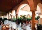 Pasillo con arcos coloniales y plantas ornamentales en el Hotel Sevilla