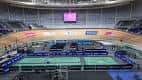 Interior de la arena configurada para eventos deportivos con cancha central y pantallas