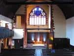 Interior del salón de eventos con altar y vitral central iluminado