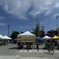 Vista general del mercado al aire libre con puestos bajo carpas blancas y amarillas
