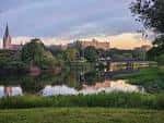 Vista panorámica del campus de Our Lady of the Lake University al atardecer con reflejo en el lago