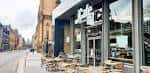 Vista exterior del iCafe Merchant City con mesas al aire libre y fachada moderna