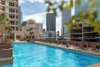 Piscina exterior del Fairmont Dallas rodeada de tumbonas y edificios urbanos