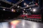 Interior del auditorio con escenario y butacas rojas