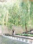 Pareja posando junto a la fuente y árboles colgantes en el patio del museo