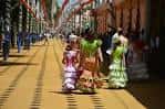 Calle decorada con banderines y mujeres vestidas con trajes típicos durante la feria