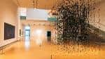Interior del museo con instalación artística suspendida y espacios abiertos