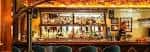 Bar Charlie's en el Minneapolis Club, ambiente acogedor con estanterías de bebidas y luces cálidas