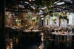 Sala de eventos decorada con mesas redondas y centros de flores colgantes