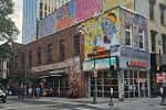 Fachada exterior del MilkBoy Philadelphia con murales coloridos en el edificio de ladrillo