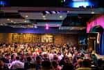 Interior del club de comedia Stand Up Live con público y escenario iluminado