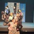 Escena de una obra de teatro con actores en el escenario